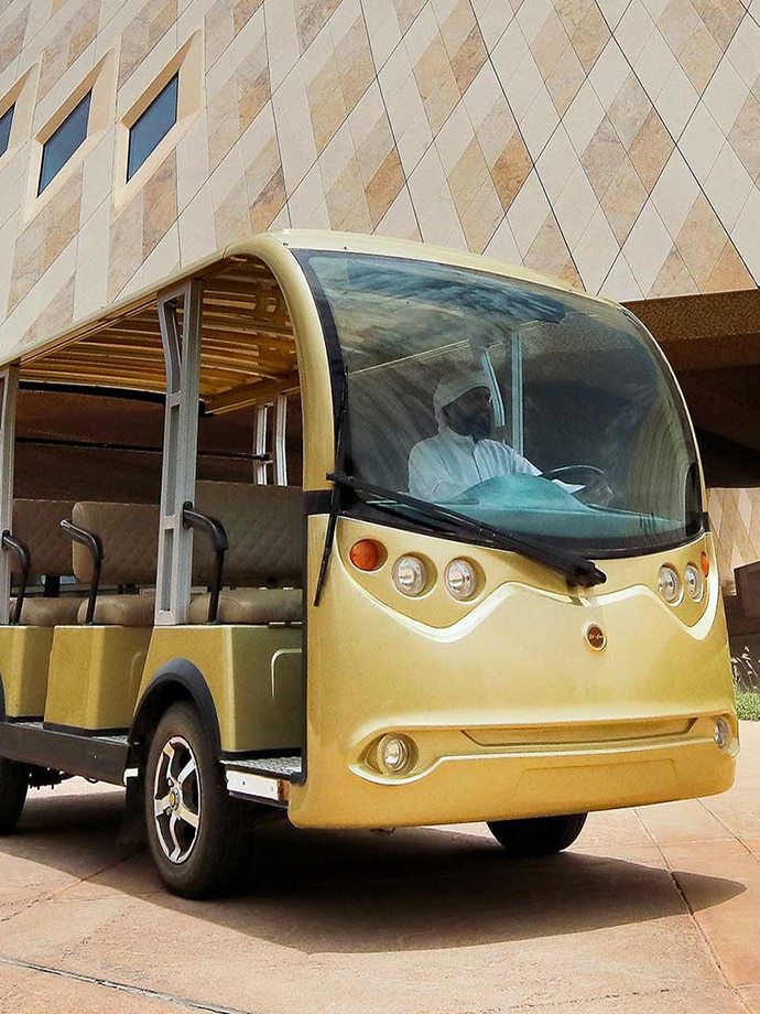 A yellow golf cart parked in front of an architecturally unique building with geometric patterns.