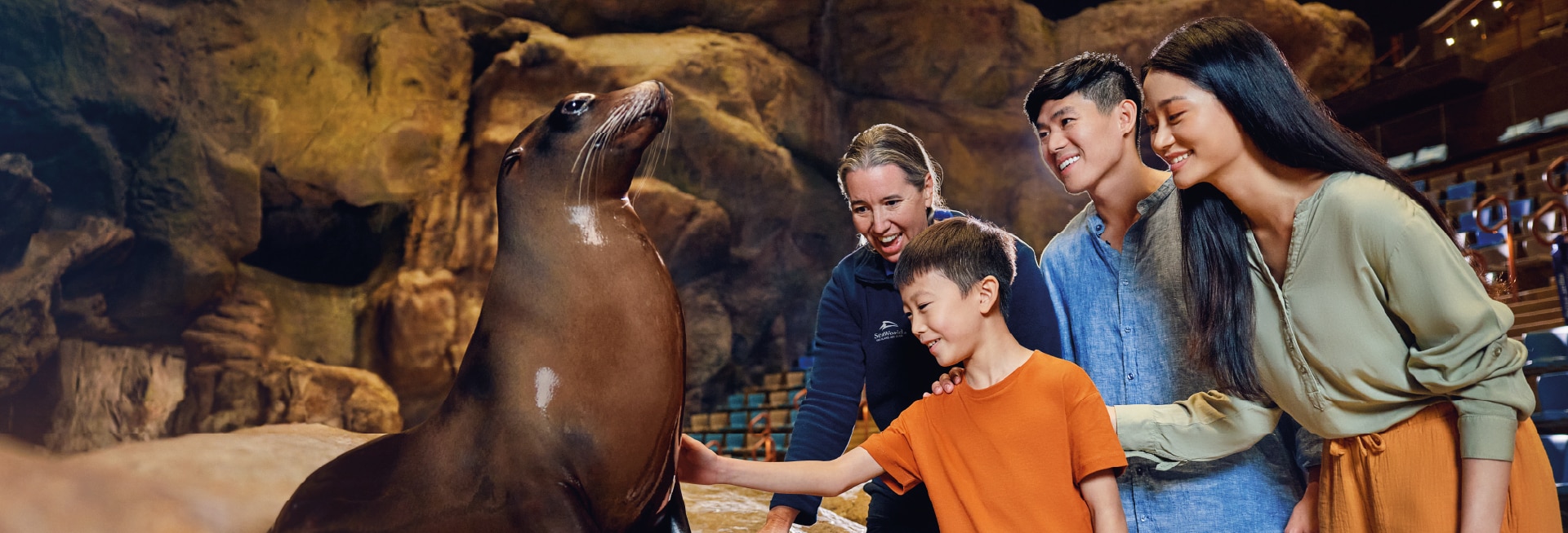 Teen girl with SeaWorld marine specialist interacting with a harbor seal