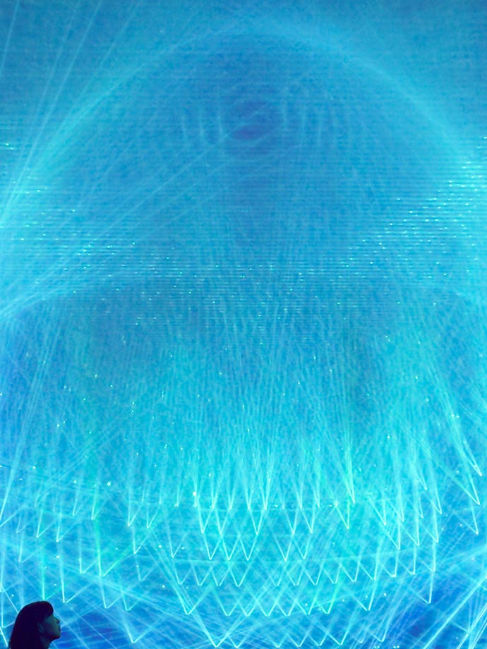 A silhouette of a lady staring up at the blue laser light streaks